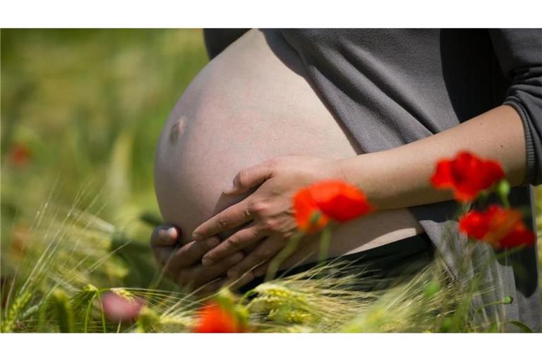  Eine im neunten Monat schwangere Frau steht in einem Getreidefeld mit Mohnblumen unweit von Frankfurt (Oder) während eines Fotoshootings (Symbolfoto).