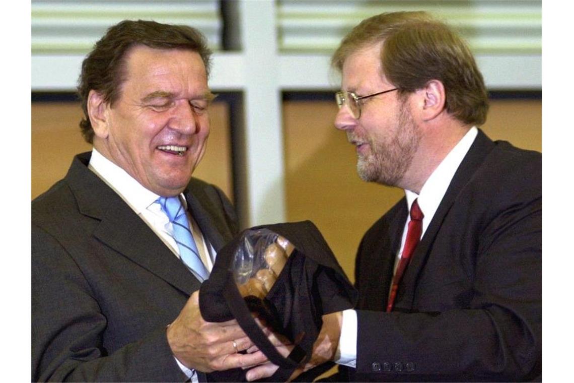 2002 erhält Gerhard Schröder (l) Currywürste von Hans-Jürgen Uhl, dem damaligen Geschäftsführer des Gesamt- und Konzernbetriebsrates von VW. Foto: Wolfgang Weihs/dpa