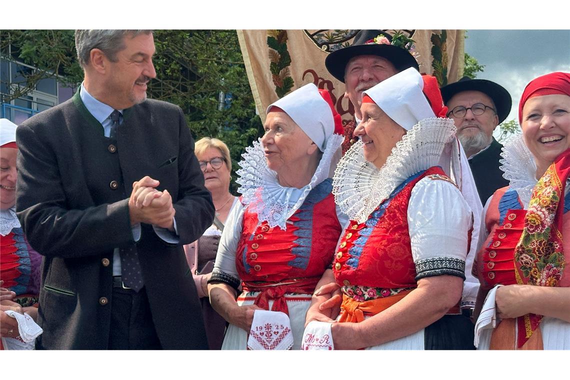 Bilder des Tages 75. Sudetendeutscher Tag: Bayerns Ministerpräsident Markus Söder (CSU, l) steht vor Beginn der Hauptkundgebung des Sudetendeutschen Tages zwischen Mitgliedern einer Trachtengruppe.