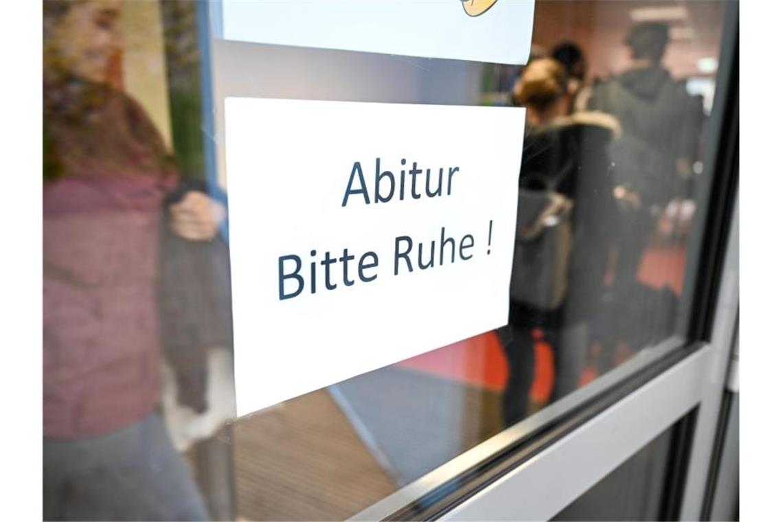 Abiturienten gehen kurz vor Beginn des Abiturs im Fach Deutsch zu ihrem Prüfungsraum an einem Schild vorbei. Foto: Felix Kästle/Archiv