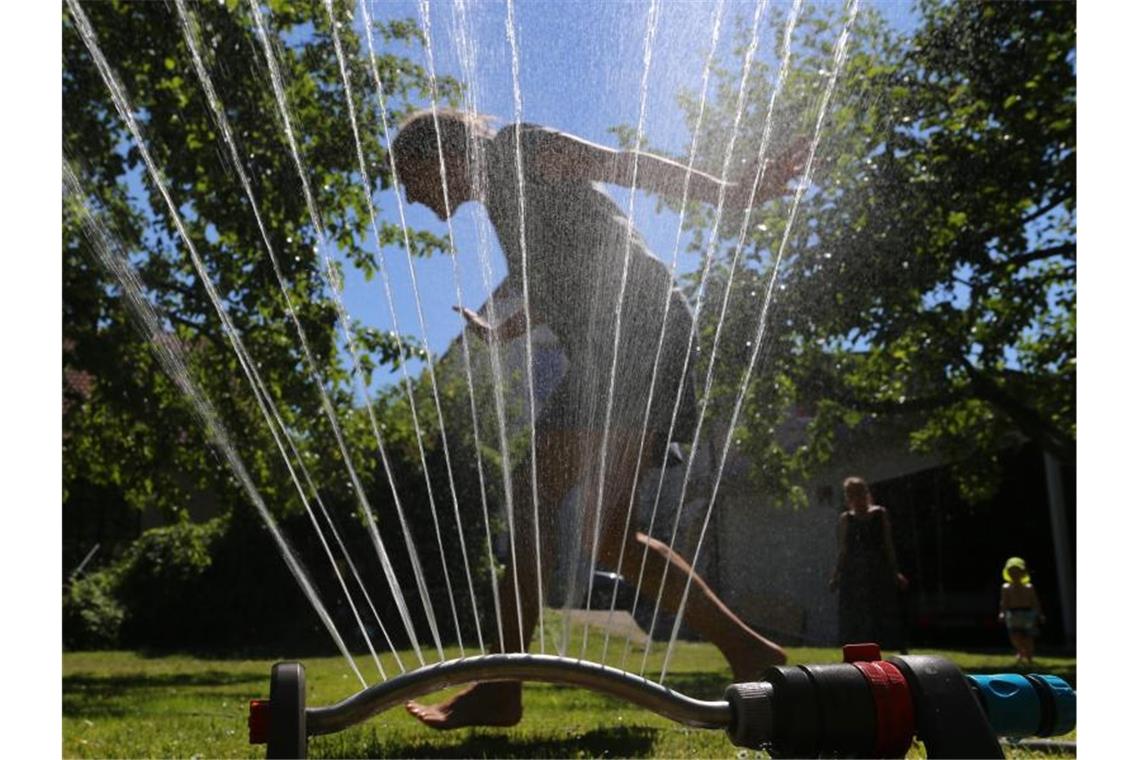 Abkühlung im Garten unter einem Rasensprenger. Foto: Karl-Josef Hildenbrand