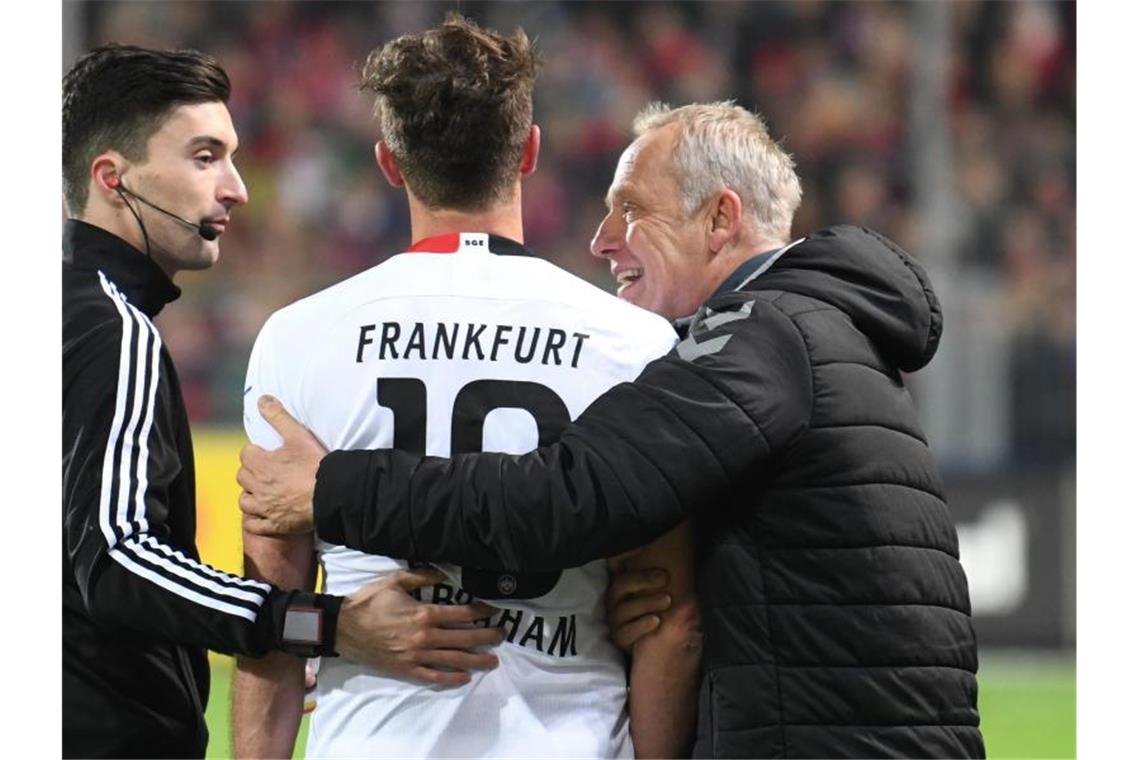 Streich scherzt nach Abrahams Rempler: DFB wird ermitteln Abraham (l.) von Frankfurt wird von Christian Streich von Freiburg nach der roten Karte umarmt. Foto: Patrick Seeger/dpa