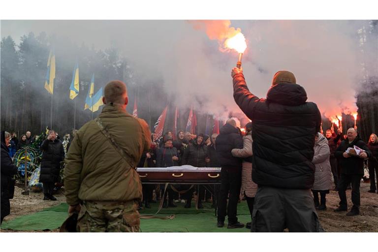 Abschied: Menschen zünden auf dem Friedhof von Slawuta in der Ukraine Fackeln während der Abschiedszeremonie für einen ukrainischen Soldaten. Der junge Mann war erst 18, als er im Ukraine-Krieg getötet wurde