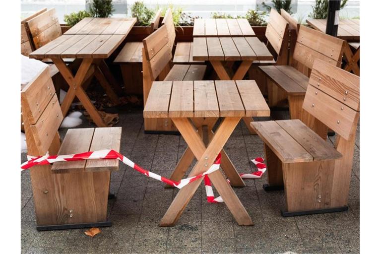 Absperrband liegt über Tischen und Stühlen vor einem Restaurant in der Innenstadt von Hannover. Foto: Julian Stratenschulte/dpa