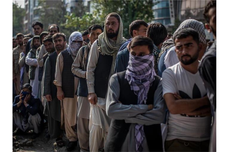 Afghanische Männer warten vor einer Bank in Kabul, um Geld abzuheben. Foto: Oliver Weiken/dpa
