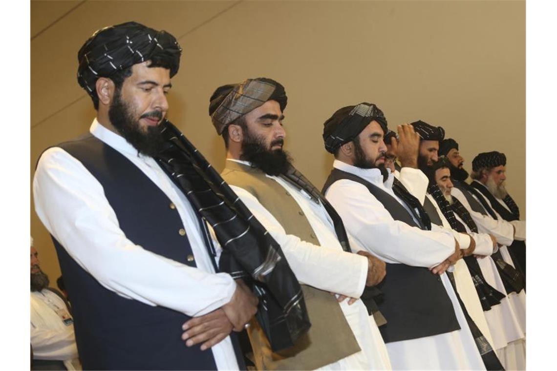 USA und Taliban unterzeichnen Abkommen über Wege zum Frieden Afghanistans Taliban-Delegation betet vor der Unterzeichnung des Abkommens zwischen Taliban und den USA. Foto: Hussein Sayed/AP/dpa