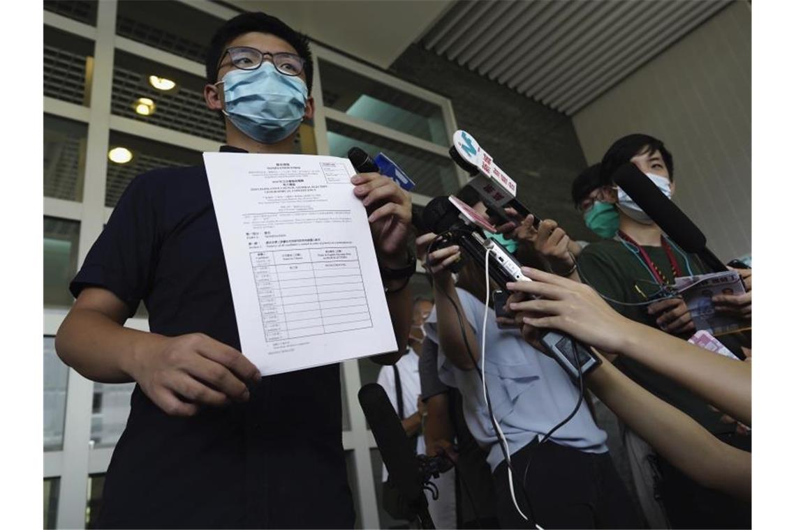 Hongkong: Aktivist Joshua Wong kandidiert bei Parlamentswahl Aktivist Joshua Wong zeigt Journalisten die Nominierungsunterlagen für die Parlamentswahl im September. Foto: Vincent Yu/AP/dpa