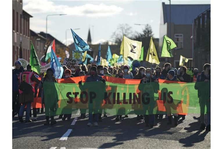 Aktivisten der Umweltschutz-Organisation Extinction Rebellion tragen bei einer Demonstration parallel zum Weltklimagipfel COP26 ein Transparent mit der Aufschrift „Stop Killing Us“ (Hört auf, uns zu töten). Foto: Alastair Grant/AP/dpa
