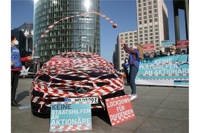 Aktivisten nehmen an einer Protest-Aktion unter dem Motto "Daimler-Dividende - Keine Staatshilfe für Aktionäre" der Bürgerbewegung Finanzwende auf dem Potsdamer Platz in Berlin teil. Foto: Wolfgang Kumm/dpa