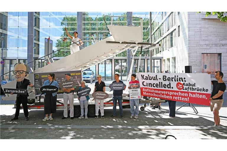 Aktivsten stehen während einer symbolischen Protestaktion am Weltflüchtlingstag zur Unterstützung mehrerer Klagen von Afghanen gegen die Bundesregierung vor dem Auswärtigen Amt.