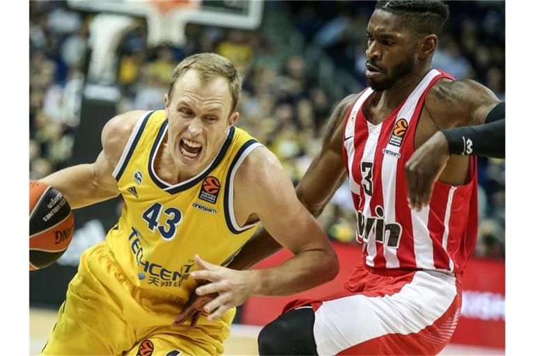 Albas Luke Sikma (l) kämpft sich durch die Abwehr von Olympiakos Piräus. Foto: Andreas Gora/dpa