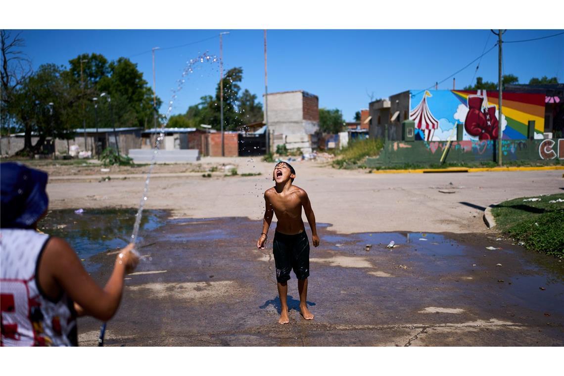 Alejo Quiroga fängt Wasser aus einem Schlauch, um sich wegen der hohen Temperaturen am Stadtrand von Buenos Aires abzukühlen.