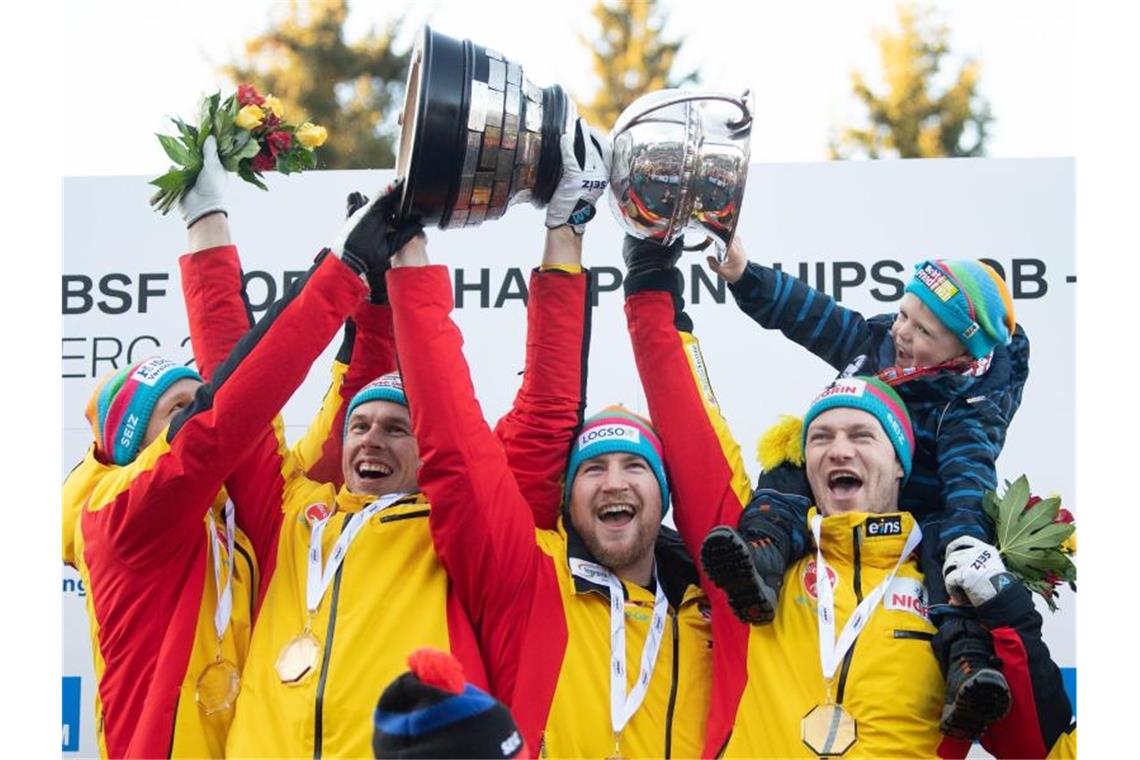 Alexander Schüller (l-r), Candy Bauer, Martin Grothkopp und Francesco Friedrich mit Sohn Karl jubeln mit dem Pokal. Foto: Sebastian Kahnert/dpa-Zentralbild/dpa