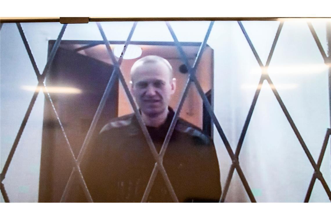 Alexej Nawalny ist auf einem Fernsehbildschirm zu sehen, als er per Video aus einem Gerichtssaal erscheint.