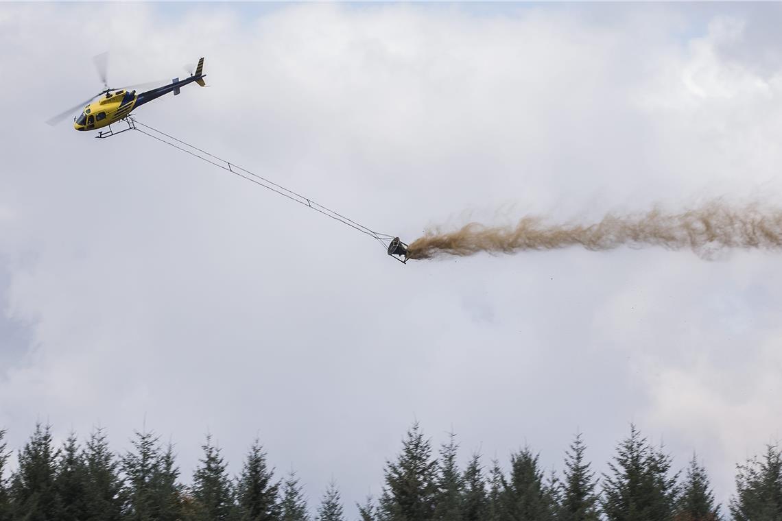 Eine Reha-Kur für die Wälder Alle ein bis zwei Minuten muss der Kalkkübel neu gefüllt werden, damit der Heli-Pilot den Inhalt über den Wäldern ausbringen kann. Archivfoto: A. Becher