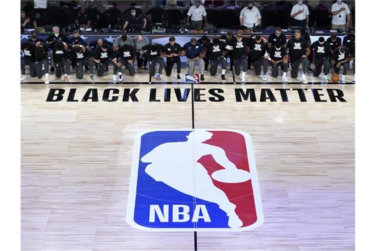 Alle Spieler der New Orleans Pelicans und von Utah Jazz knien vor einem „Black Lives Matter“-Schriftzug. Foto: Ashley Landis/Pool AP/dpa
