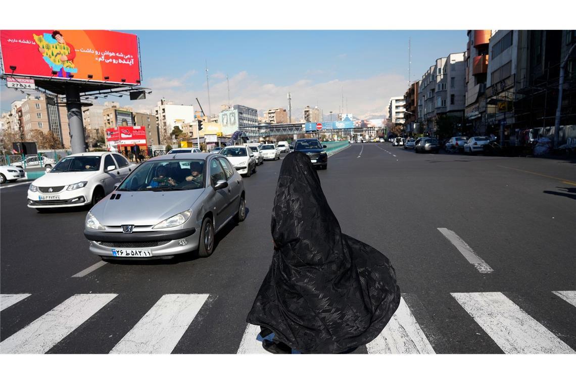 Alltag in Teheran:  Verschleierte Frau überquert Kreuzung im Zentrum
