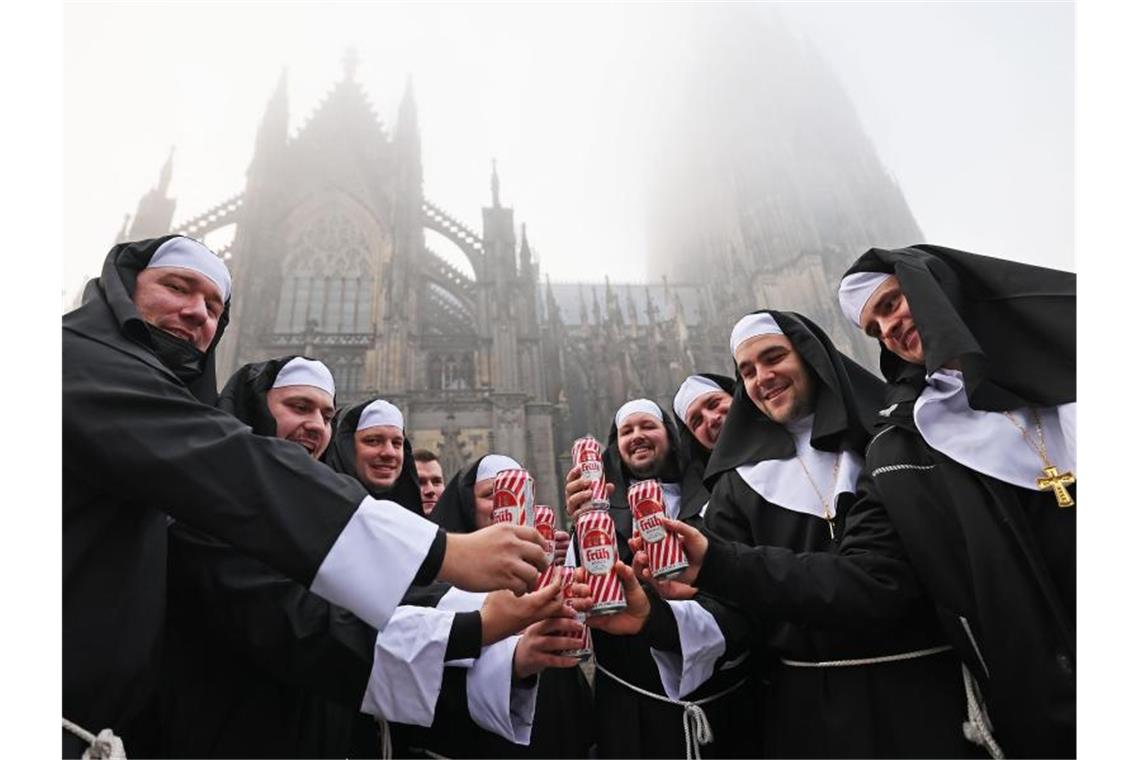 Als Nonnen verkleidete Karnevalisten feiern vor dem Dom in Köln. Foto: Oliver Berg/dpa