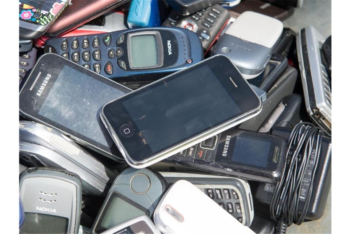 Alte Mobiltelefone liegen in einer Schubkarre. Foto: Maurizio Gambarini/dpa