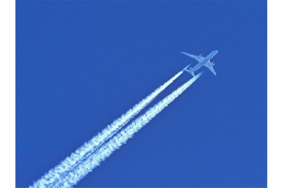 Am blauen Himmel fliegt ein Flugzeug und hinterlässt Kondensstreifen. Foto: Patrick Pleul/dpa-Zentralbild/dpa/Symbolbild