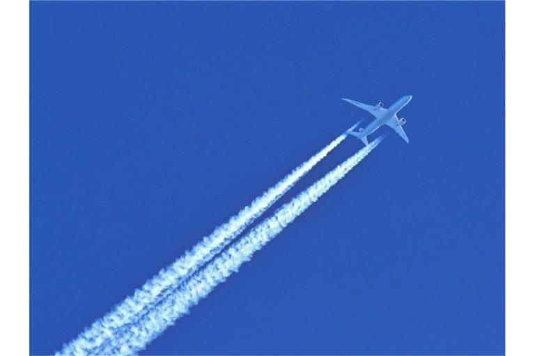 Am blauen Himmel fliegt ein Flugzeug und hinterlässt Kondensstreifen. Foto: Patrick Pleul/dpa-Zentralbild/dpa/Symbolbild