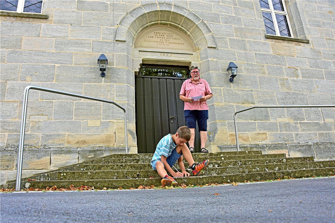 Beim BKZ-Sommerquiz in Althütte gehts vom Fäßle bis zur katholischen Kirche Am Eingang der Evangelischen Kirche müssen Hartmut und Julian Reichert nach dem achten Wort der Inschrift suchen. Fotos: Tobias Sellmaier