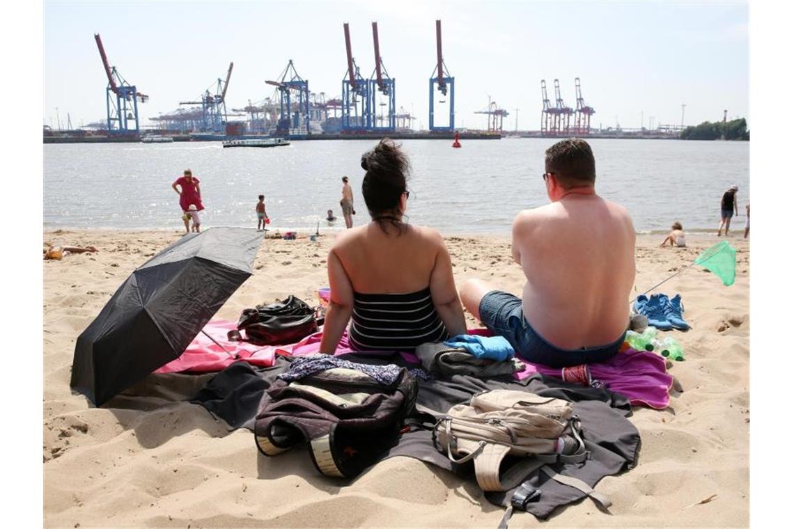 Am Elbstrand in Hamburg: Ausflügler sitzen bei hochsommerlichen Temperaturen am Strand von Övelgönne. Foto: Bodo Marks