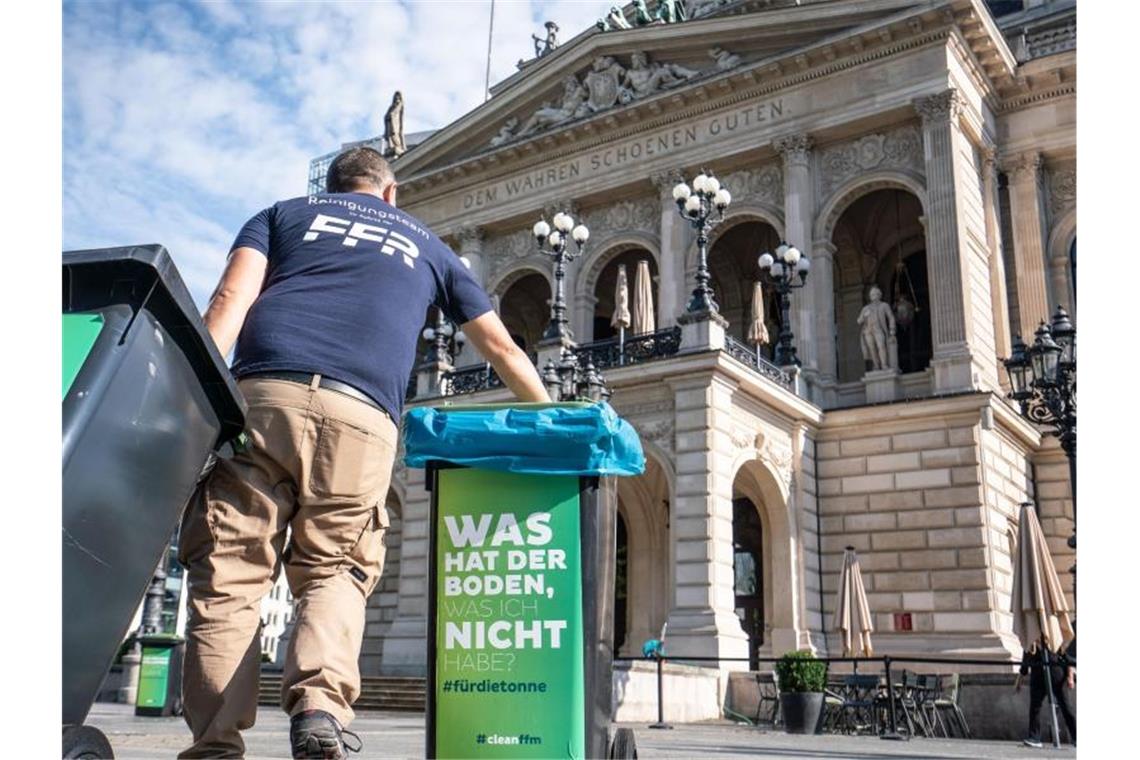 Nächtliche Krawalle in Frankfurt: Gewalt gegen Beamte Am Morgen nach den Krawallen stellt ein Mitarbeiter der Stadtreinigung vor der Alten Oper geleerte Mülltonnen auf. Foto: Frank Rumpenhorst/dpa