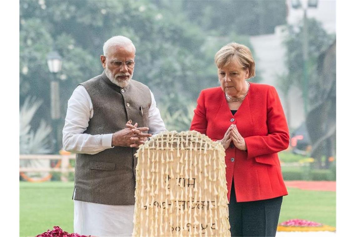 An dem Ort, an dem Gandhi erschossen wurde, faltet Angela Merkel neben Premier Narendra Modi ihre Hände zum Gedenken. Foto: Michael Kappeler/dpa