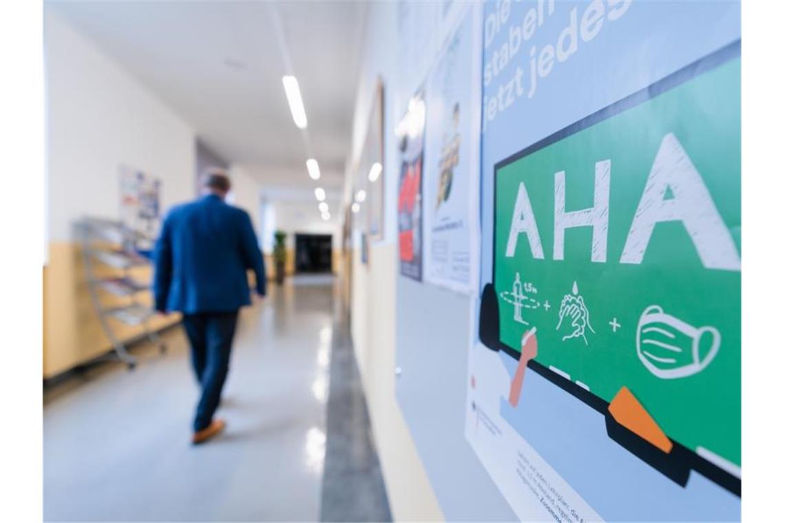 An der Wand eines Flurs in einem Gymnasium ist ein Hinweis auf die AHA-Regeln angebracht. Foto: Nicolas Armer/dpa