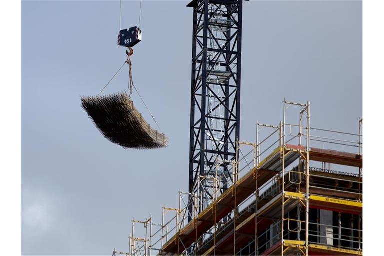 An einem Baukran wird Baumaterial auf der Baustelle des Quartiers Heidestrasse in Berlin transportiert. Foto: Carsten Koall/dpa