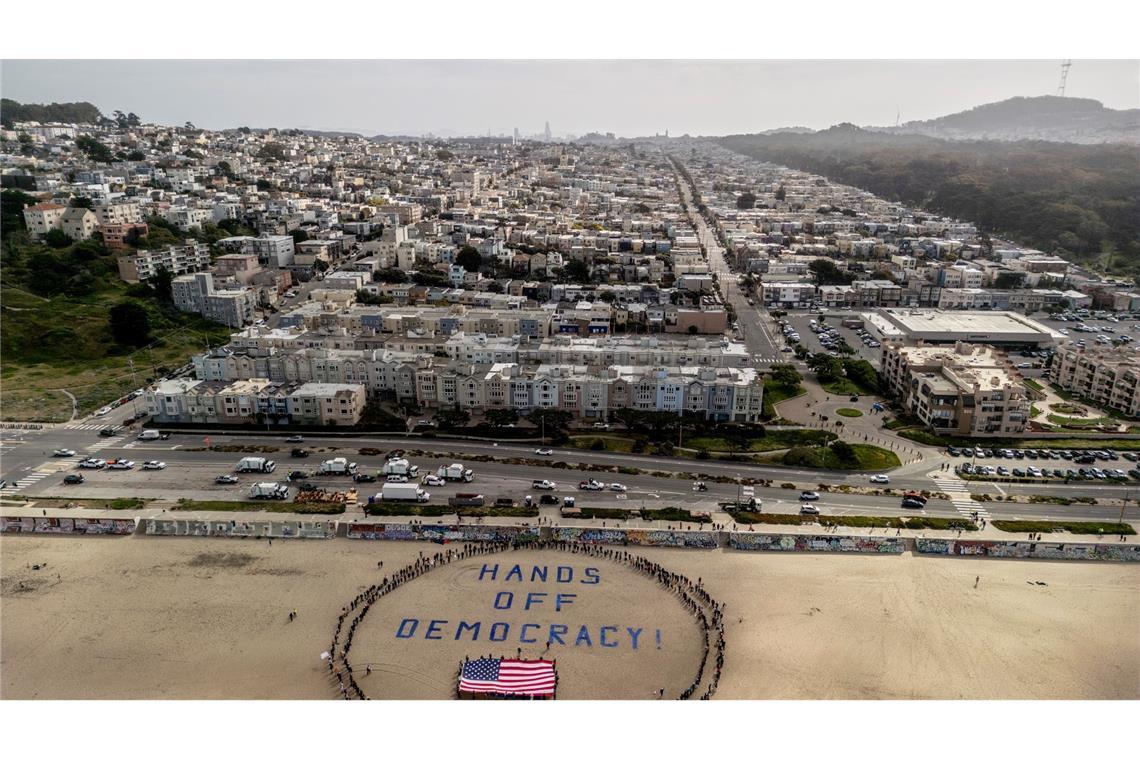 Landesweite Proteste gegen Trump in den USA An einem Strand im Bundesstaat Kalifornien bildeten Demonstranten einen menschlichen Kreis um eine US-Flagge und den Slogan "Hände weg von der Demokratie!".