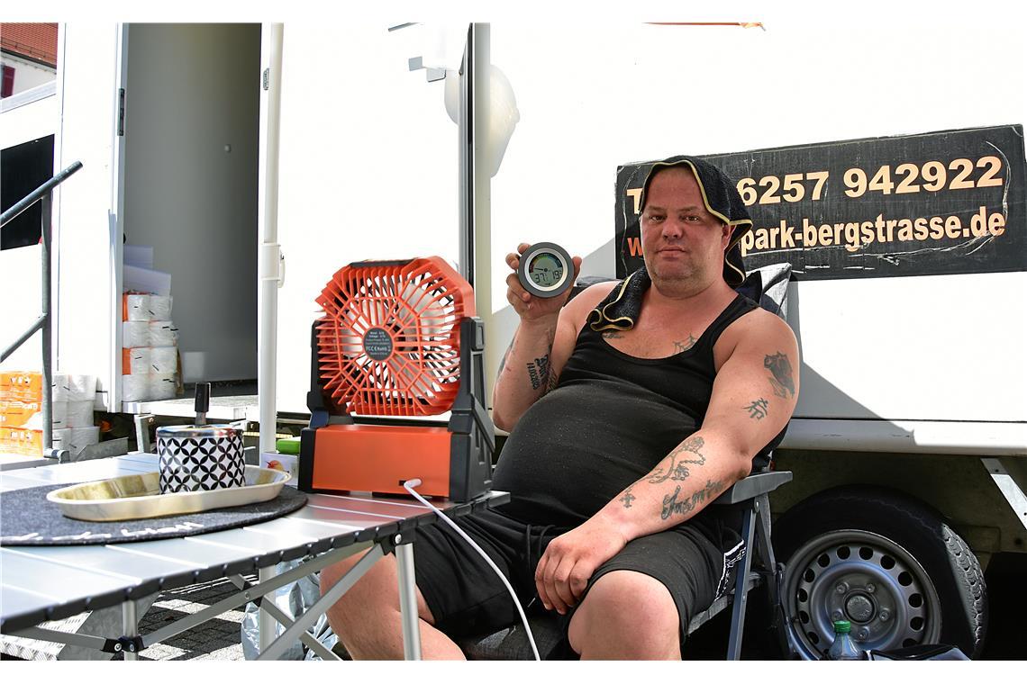 An einem Toilettenwagen in der Marktstraße sitzt Daniel Jost. Das Thermometer ze...