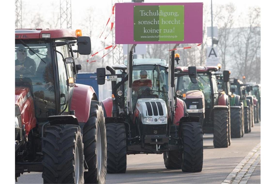 An einem Traktor hängt bei einer Demonstration von Bauern ein Schild mit der Aufschrift "Tschuldigung sonscht horcht koiner zua!". Foto: Sebastian Gollnow/dpa