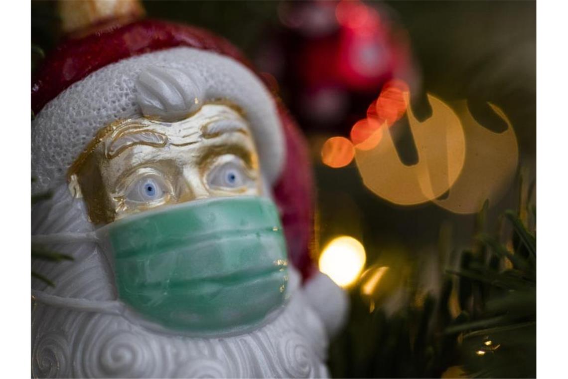 Corona-Regeln an Weihnachten weitgehend eingehalten An einem Weihnachtsbaum hängt Weihnachtsschmuck in Form eines Weihnachtsmannes, der eine Maske trägt. Foto: Tom Weller/dpa/Archivbild