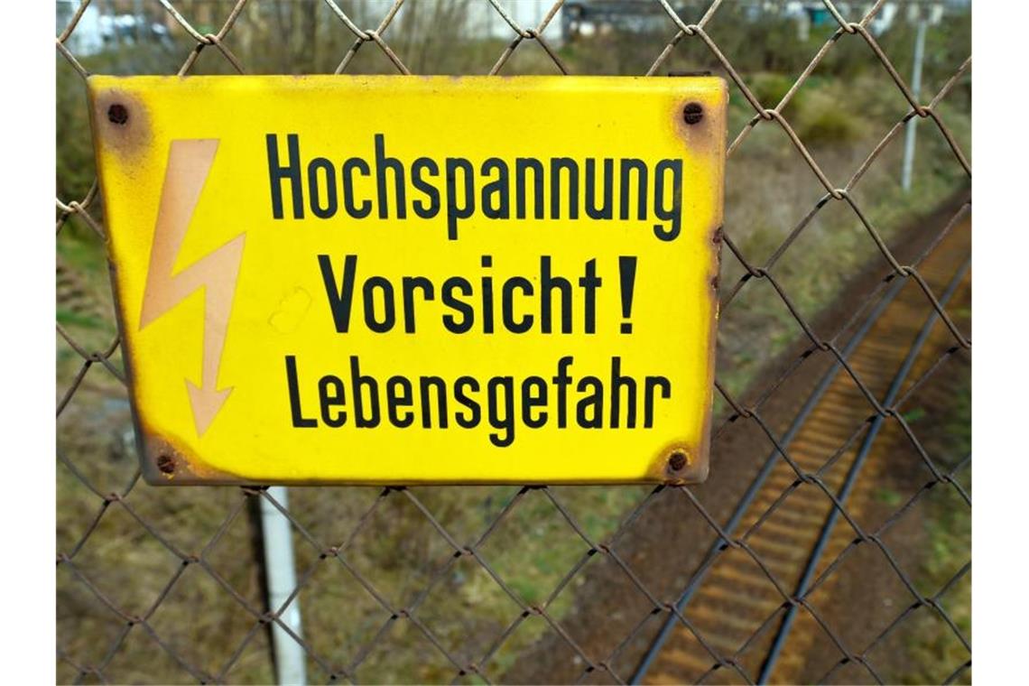An einer Eisenbahnbrücke warnt ein Schild vor lebensgefährlicher Hochspannung. Foto: Patrick Pleul/Symbolbild