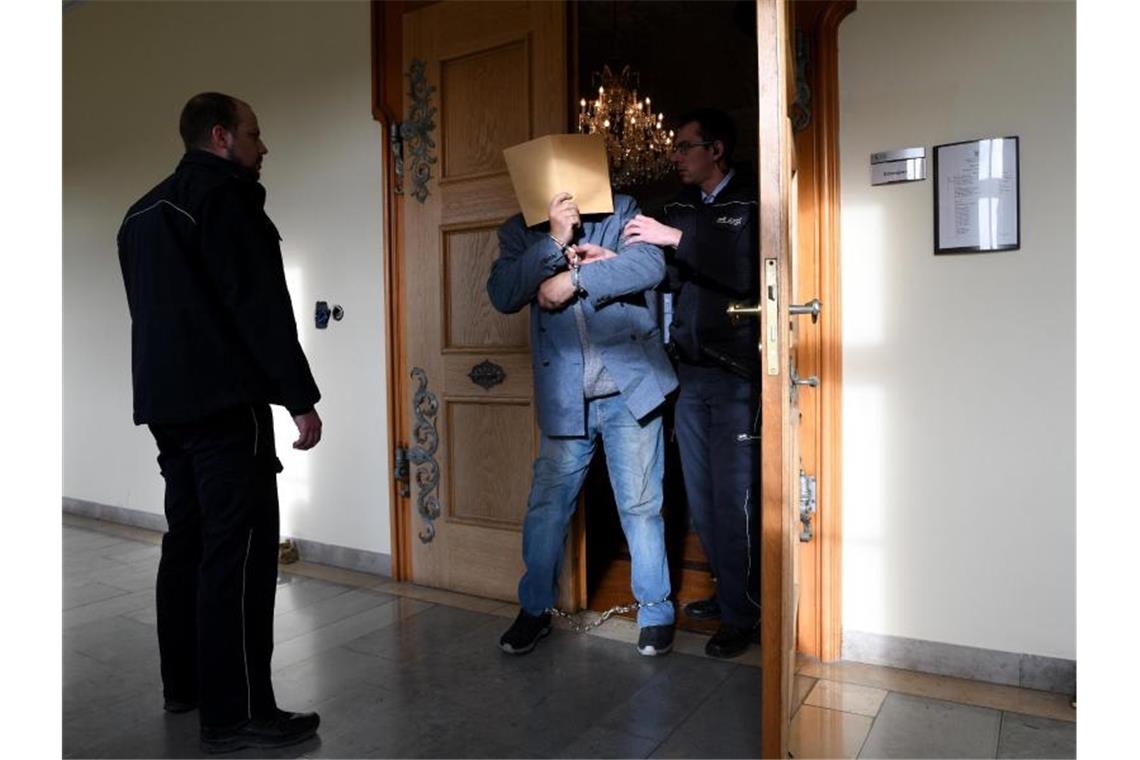 Zwei Opfer mit Kettensägen zerlegt: Mordprozess in Ellwangen An Händen und Füssen gefesselt wird der angeklagte Vater in einer Verhandlungspause aus dem Sitzungssaal in Ellwangen geführt. Foto: Stefan Puchner/dpa