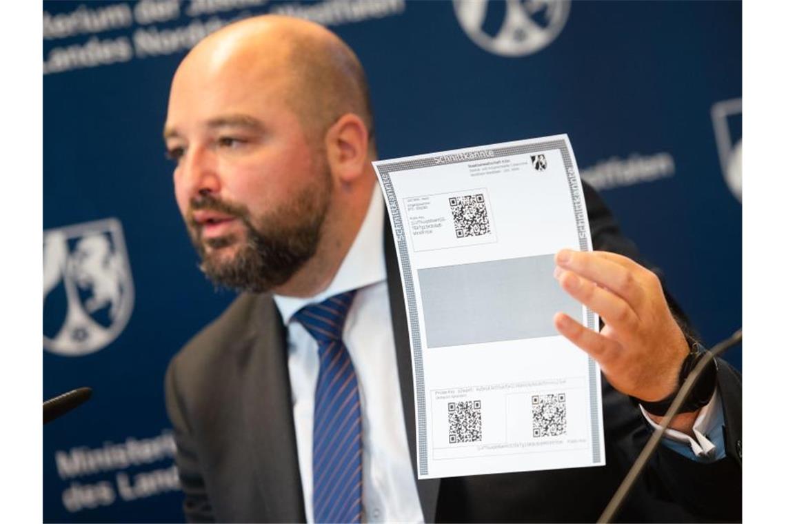 Andreas Brück, Staatsanwalt bei der Zentral- und Ansprechstelle Cybercrime (ZAC NRW), mit einem Paper Wallet für Bitcoin. Foto: Marius Becker/dpa