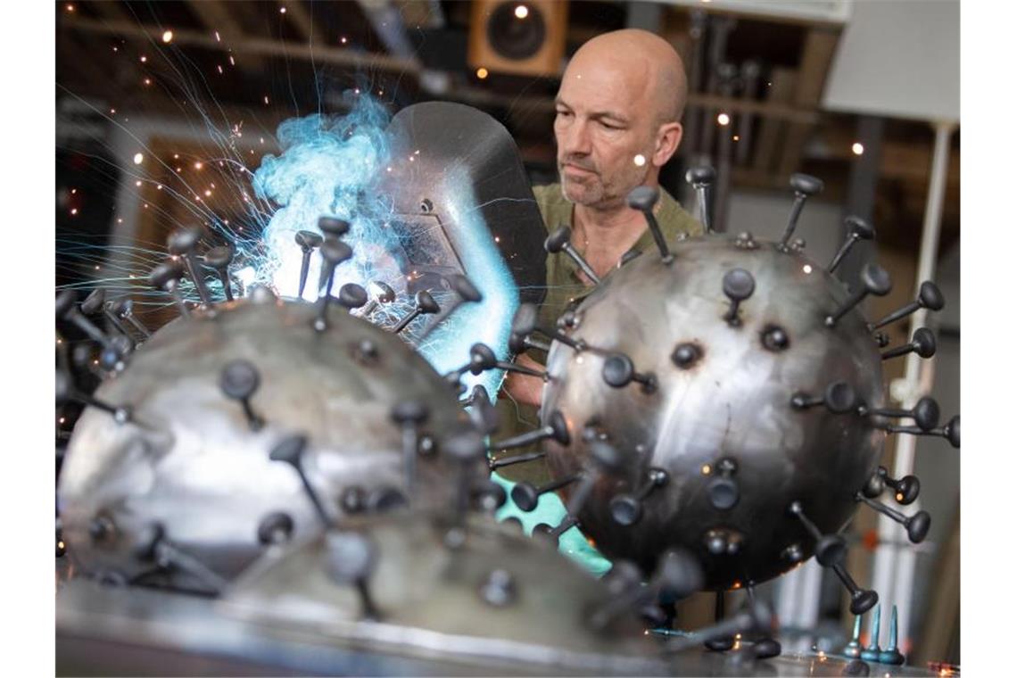Andreas Furtwängler arbeitet mit einem Schweißgerät an Metallskulpturen, die den Corona-Virus darstellen sollen. Foto: Marijan Murat/dpa/Archivbild
