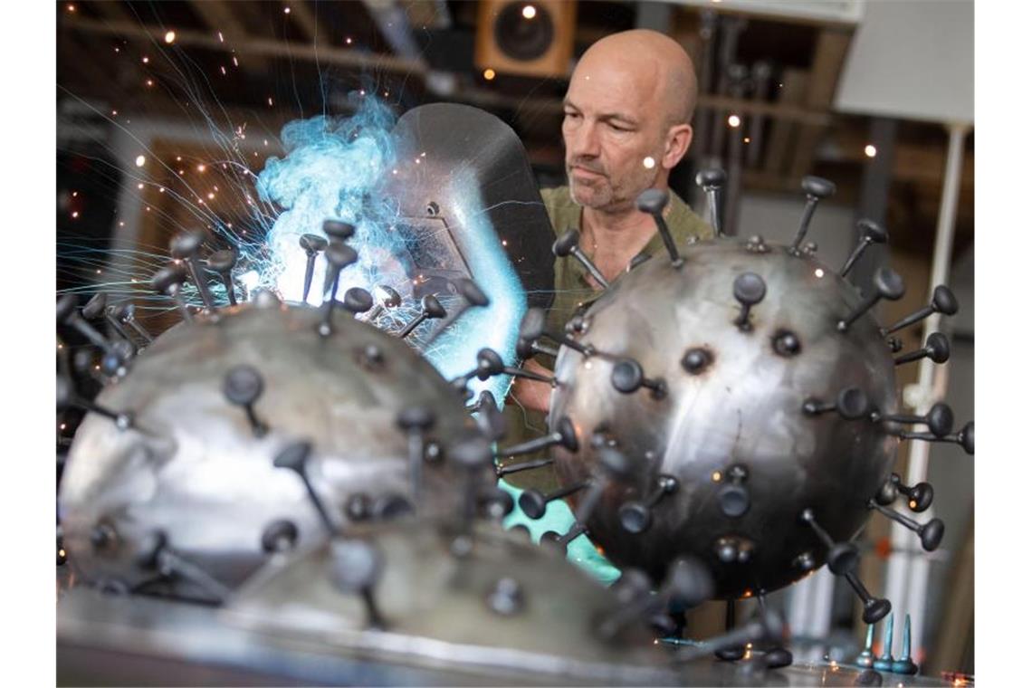 Viren aus Stahl: Künstler fertigt Corona-Skulpturen an Andreas Furtwängler arbeitet mit einem Schweißgerät an Metallskulpturen, die den Corona-Virus darstellen sollen. Foto: Marijan Murat/dpa/Archivbild
