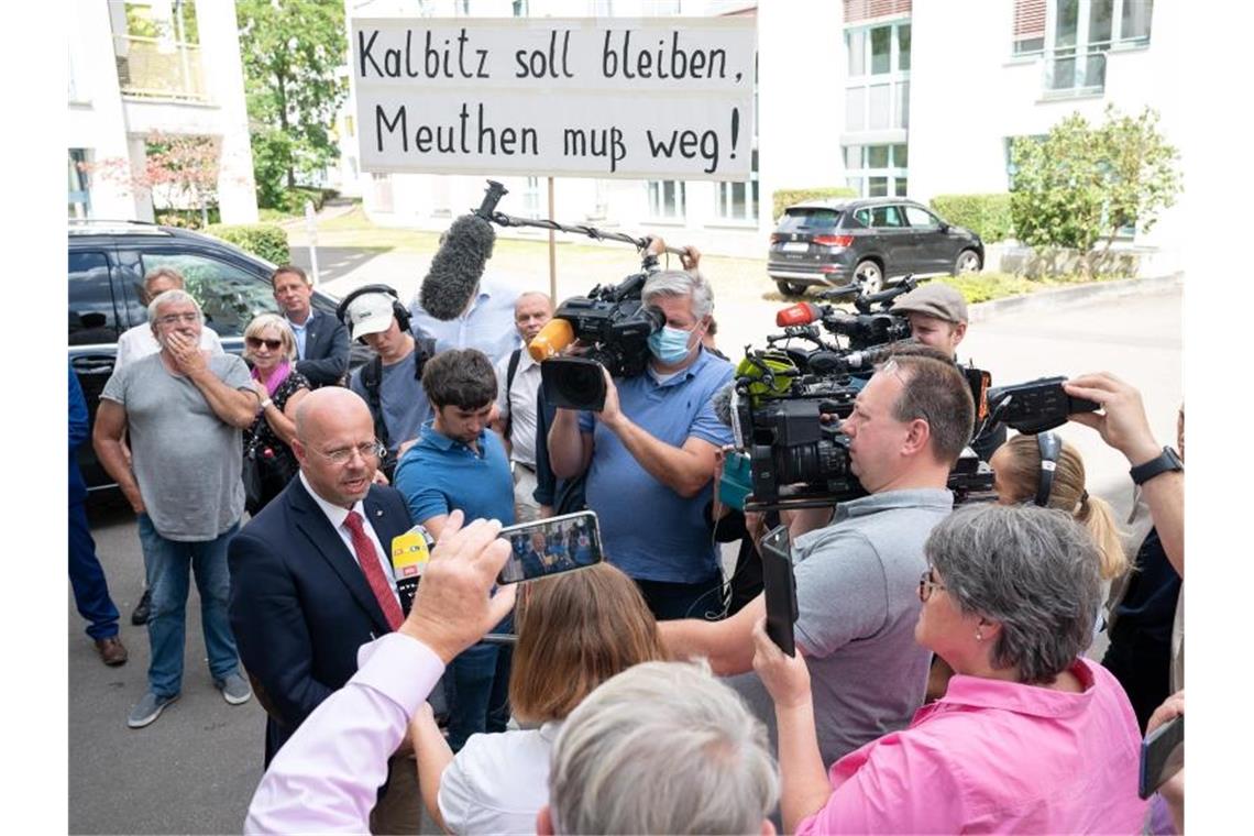 Andreas Kalbitz im Gespräch mit Journalisten - im Hintergrund haben sich Unterstützer versammelt. Foto: Sebastian Gollnow/dpa