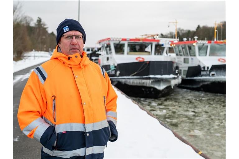 Andreas Schultz, Schiffsführer vom Eisbrecher „Elbe“, steht vor den beiden Eisbrechern „Elbe“ und „Biber“ in Scharnebeck. Foto: Philipp Schulze/dpa