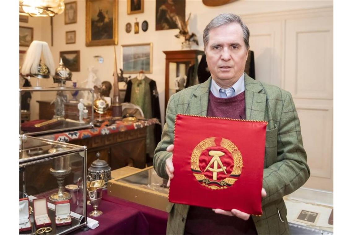 Honecker-Devotionalien bringen 120.000 Euro bei Auktion Andreas Thies hält in seinem Aktionshaus ein KFZ Stander Erich Honekers als Partei und Staatsratsvorsitzenden der DDR. Foto: Tom Weller/dpa