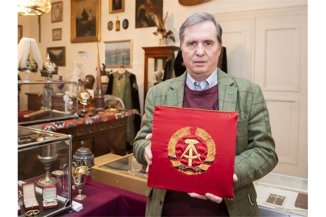Honecker-Devotionalien bringen 120 000 Euro bei Auktion Andreas Thies mit einem KFZ-Stander von Erich Honeker als DDR-Partei- und Staatsrats-Vorsitzenden. Foto: Tom Weller/dpa