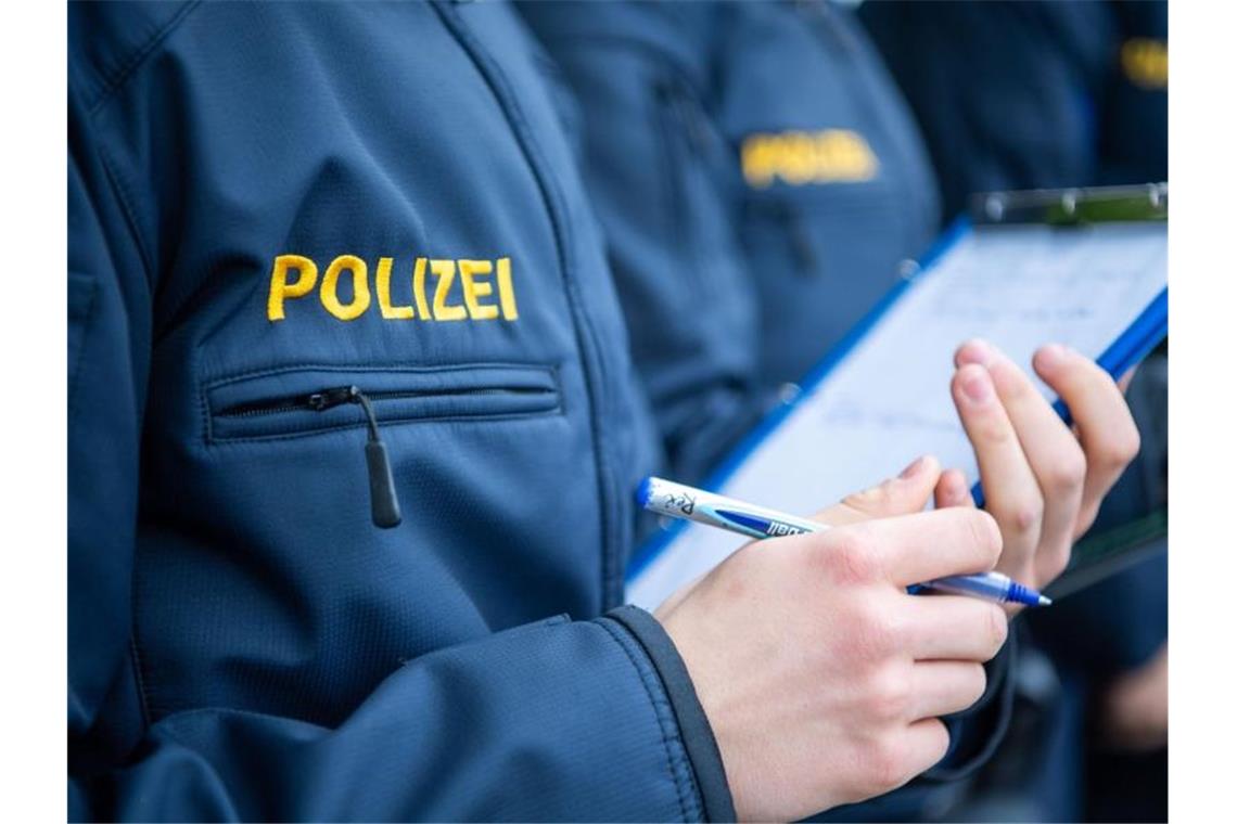 Angehende Streifenpolizisten notieren sich in einer Polizeischule etwas auf einer Notizmappe. Foto: Lino Mirgeler/dpa/Archivbild