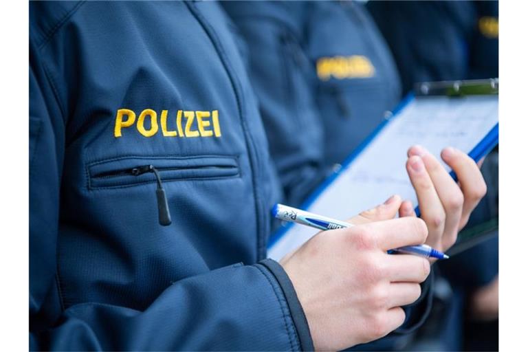 Angehende Streifenpolizisten notieren sich in einer Polizeischule etwas auf einer Notizmappe. Foto: Lino Mirgeler/dpa/Archivbild