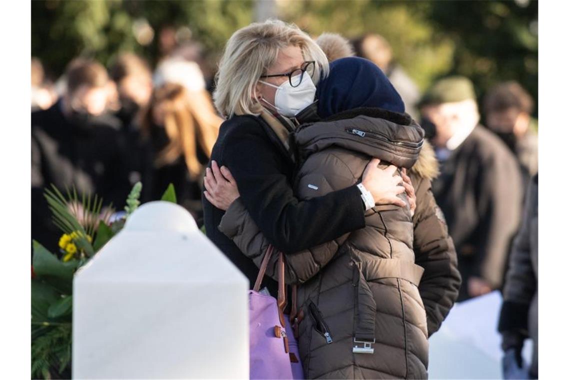 Anschlag in Hanau: „Kein Vergeben - kein Vergessen“ Angehörige umarmen sich vor dem Grab eines der Opfer des Anschlags. Foto: Boris Roessler/dpa POOL/dpa