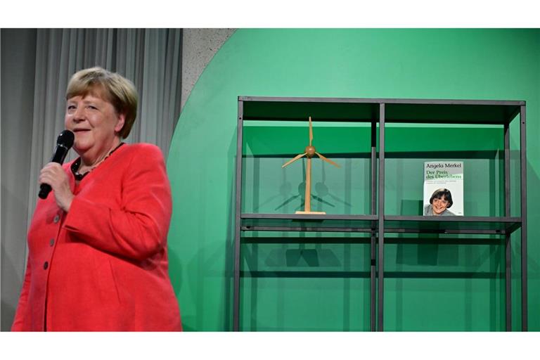 Angela Merkel (CDU), Bundeskanzlerin a.D. und ehemalige Bundesumweltministerin, spricht auf der Bühne beim Festakt "Seit 40 Jahren NaturVerbunden" zum 40. Jubiläum des Bundesumweltministeriums im Café "Moskau", während im Hintergrund ihr Buch mit dem Titel „Der Preis des Überlebens“ zu sehen ist.