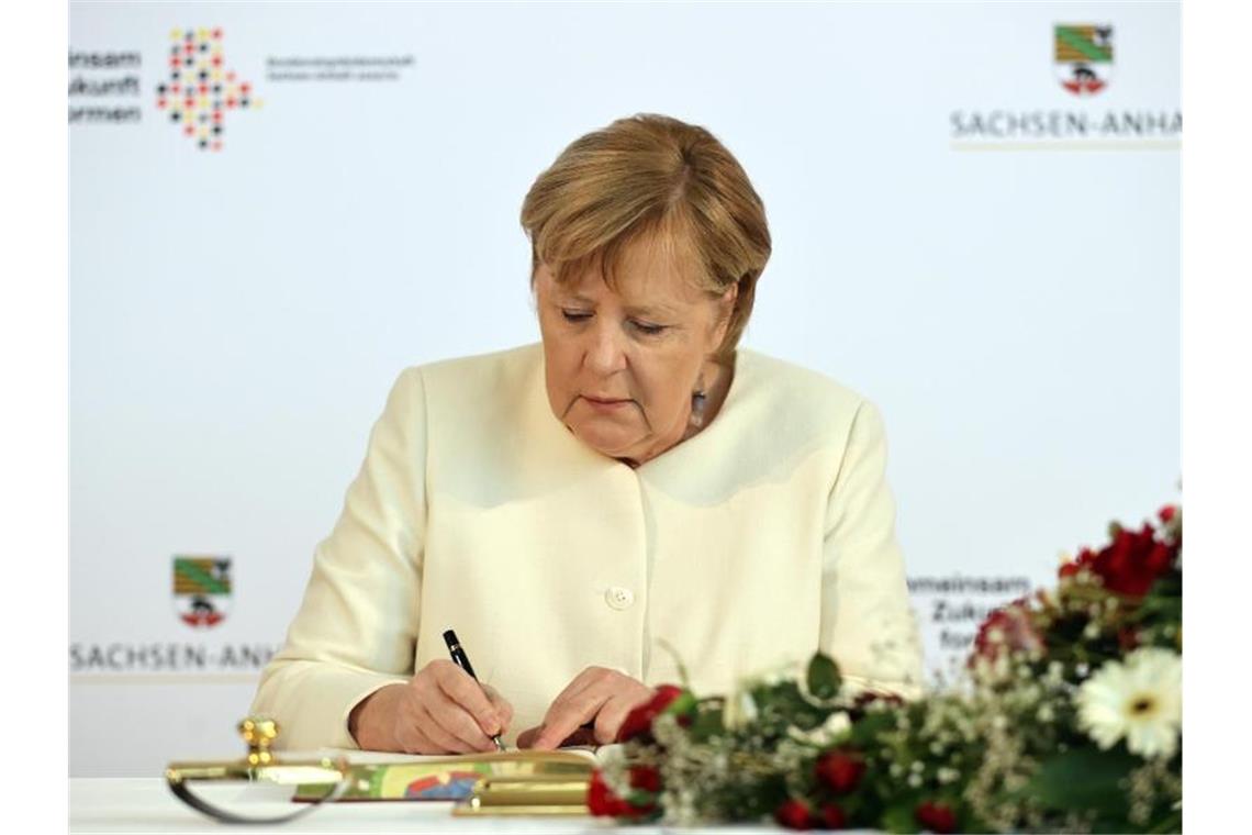 Merkel fordert Einsatz für die Demokratie Angela Merkel trägt sich vor Beginn des Festakts in das Goldene Buch der Stadt Halle ein. Foto: Jan Woitas/dpa POOL/dpa