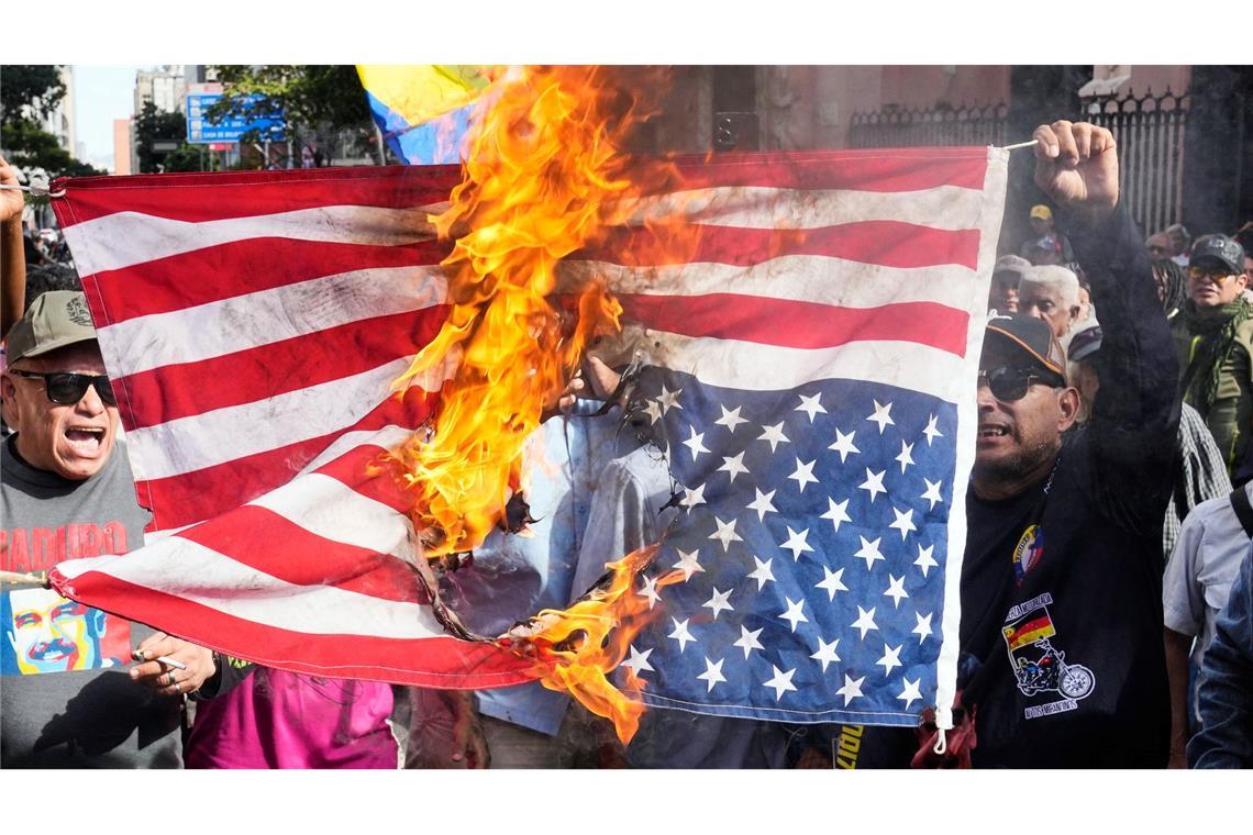 Anhänger der Regierung verbrennen eine US-Flagge in Caracas, nachdem US-Präsident Trump bekannt gegeben hatte, dass die US-Streitkräfte den venezolanischen Präsidenten Maduro und seine Frau gefangen genommen haben.